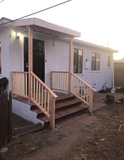 A small white house with a new wooden porch at dusk.