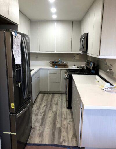 A modern kitchen with stainless steel appliances, white cabinetry, and wood-look flooring.