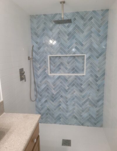 Modern bathroom with herringbone pattern tile shower and rain showerhead.