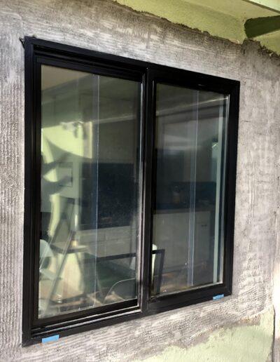 New black-framed windows installed in a gray concrete wall.