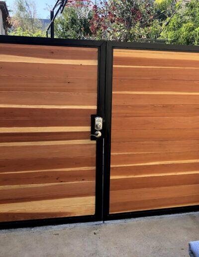 Wooden dual swing gate with modern lock, installed on a residential property.