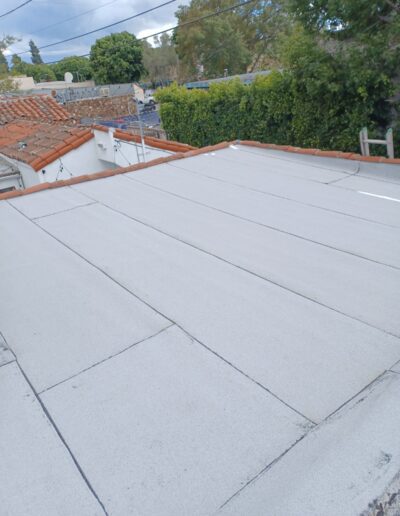 Flat concrete roof juxtaposed with tiled roofing in a residential area.