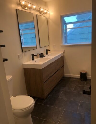 Modern bathroom with a vanity unit, two mirrors, and a toilet.