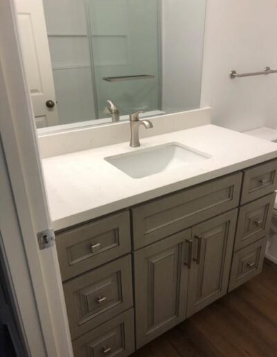 Modern bathroom vanity with a white countertop, built-in sink, and wooden cabinets.